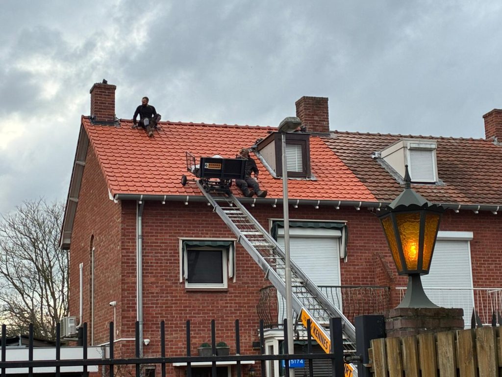 Dakwerken op een bakstenen huis met ladder.